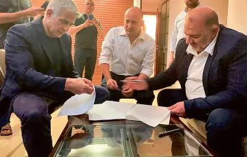 Od lewej: Jair Lapid, Naftali Bennett i Mansur Abbas podpisują porozumienieo koalicji rządowej. Ramat Gan, Izrael, 2 czerwca 2021 r. (zdjęcie zrobione smartfonem). / UNITED ARAB LIST RAAM / AFP / EAST NEWS