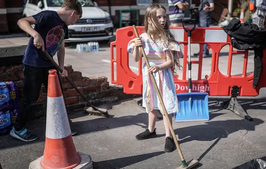Mieszkańcy Southport (na zdjęciu: rodzeństwo Evelyn i Sebastian Taylor) sprzątają ulicę przy zniszczonym przez demonstrantów meczecie, 31 lipca 2024 r. // Fot. Christopher Furlong / Getty Images