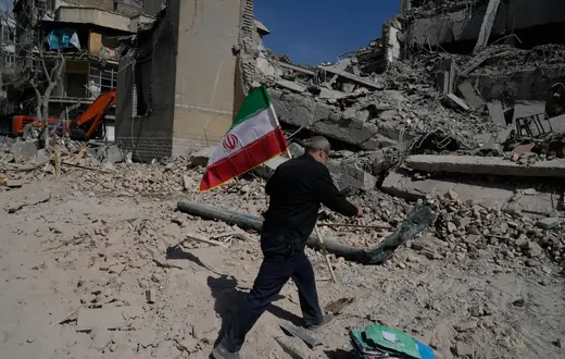 Mężczyzna niesie irańską flagę na gruzach budynków w Teheranie zbombardowanych podczas amerykańsko-izraelskiej kampanii wojskowej w Iranie, w środę 4 marca 2026 r. / Vahid Salemi/Associated Press/East News