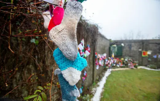 Dziecięce skarpetki na murze dawnego "domu opieki" w Tuam, gdzie zakonnice pochowały ok. 800 niemowląt. Urodzone z ciąży pozamałżeńskiej, zostały uznane przez siostry za grzeszne i pochowane bezimiennie. / Fot. Paul Faith / AFP / East News / 