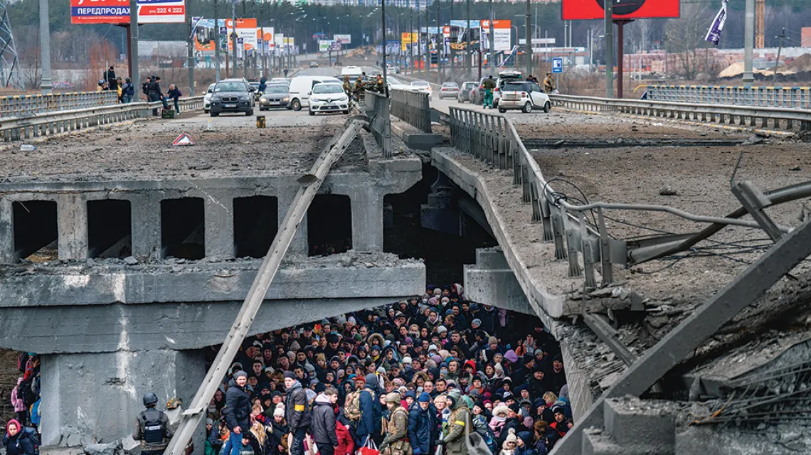 Uciekinierzy z Kijowa pod mostem zniszczonym w wyniku rosyjskiego nalotu czekają na ewakuację. Irpień, przedmieścia ukraińskiej stolicy, 5 marca 2022 r. / EMILIO MORENATTI / AP / EAST NEWS