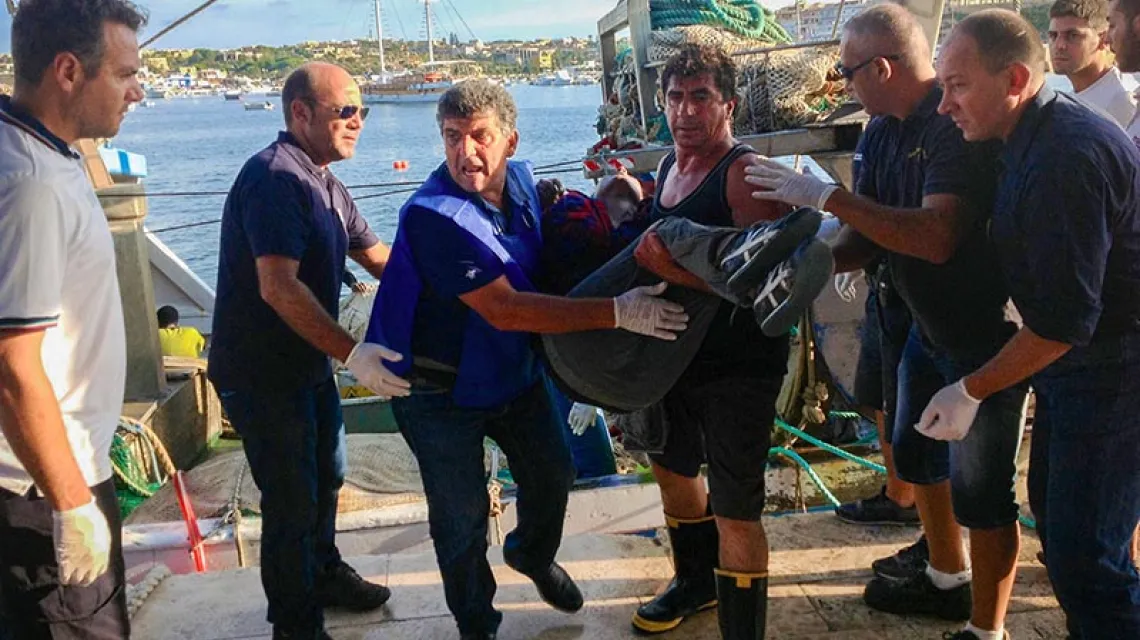 Pietro Bartolo (trzeci od lewej) podczas akcji pomocy migrantom na nabrzeżu Lampedusy. / Fot. Nino Randazzo