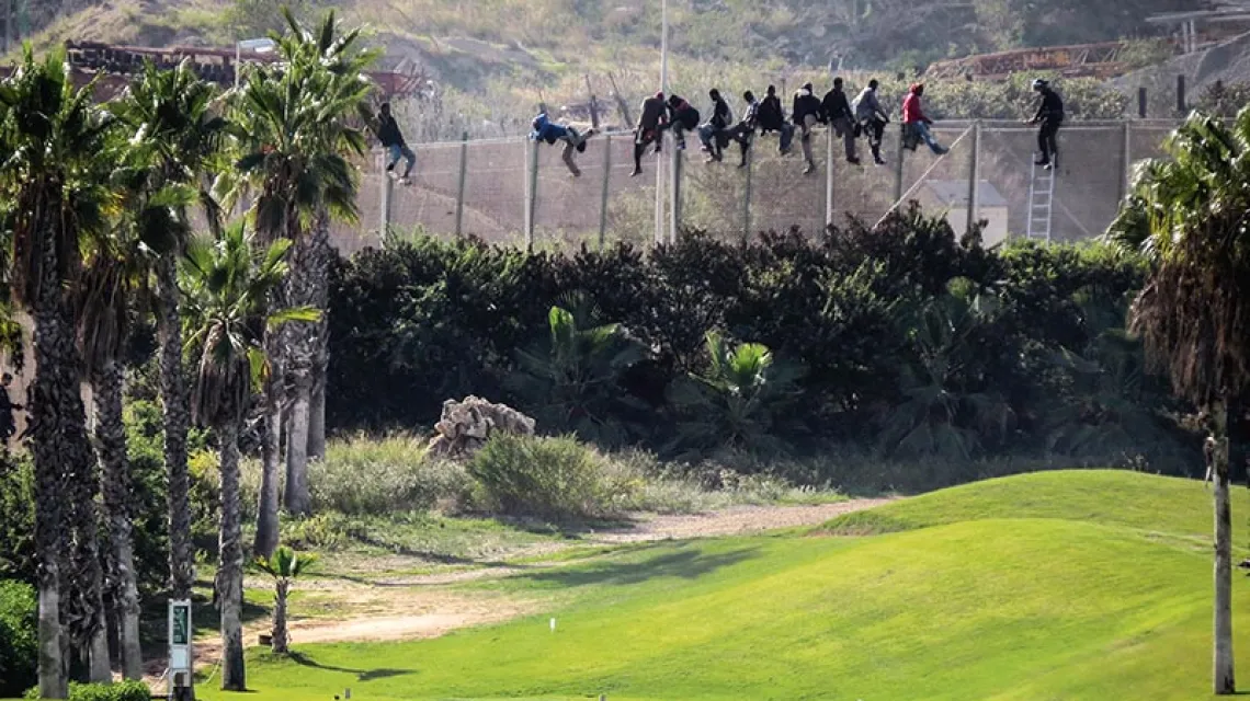 Afrykańscy migranci na ogrodzeniu pola golfowego w hiszpańskiej enklawie Melilla w Maroku, 22 października 2014 r.  / Fot. STRINGER / REUTERS / FORUM