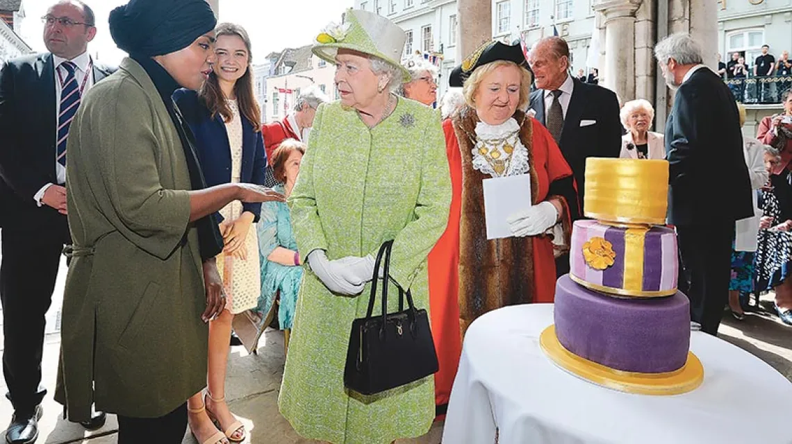 Nadiya Hussain prezentuje Elżbiecie II wykonany przez siebie tort na 90. urodziny królowej. Wkrótce okaże się, że wokół tego tortu wybuchnie burza. Londyn, kwiecień 2016 r. / Fot. John Stillwell / PA / EAST NEWS