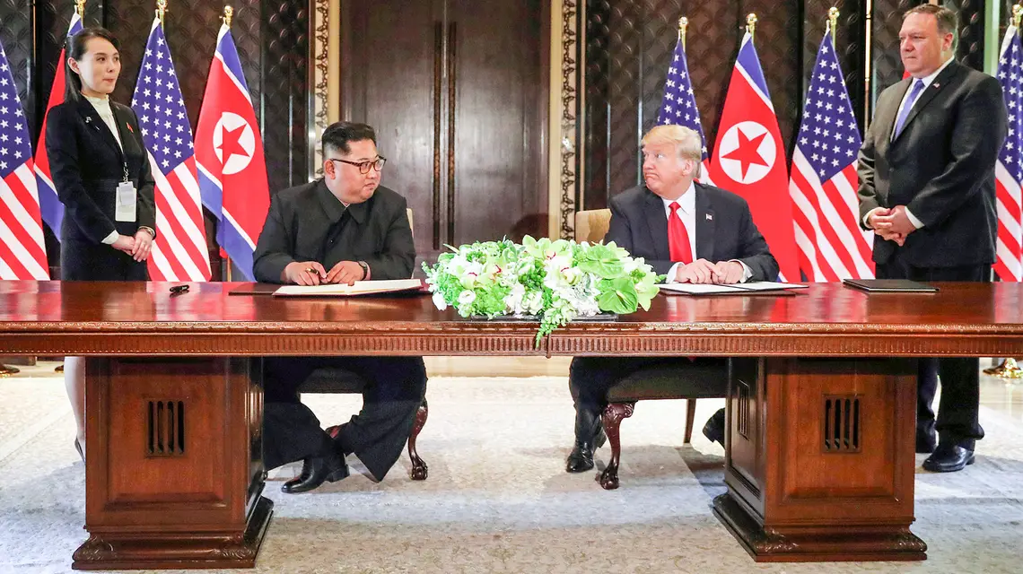 Kim Dzong Un podpisuje porozumienie z Donaldem Trumpem. Obaj politycy spotkali się trzykrotnie, a Trump chwalił się, że ma wpływ na Kima. Obok stoją Kim Jo Dzong i sekretarz stanu USA Mike Pompeo. Singapur, czerwiec 2018 r. // Fot. JONATHAN ERNST / Reuters / Forum