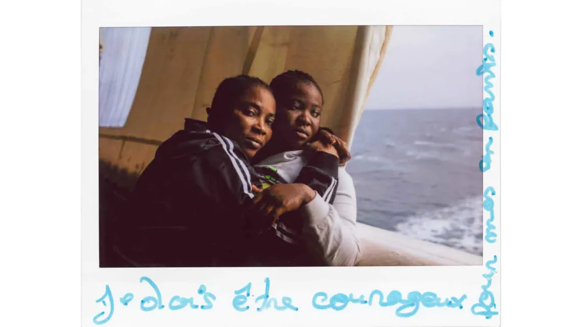 Zdjęcie Bintou (po lewej) z podpisem „muszę być odważna dla moich dzieci”. Bintou pochodzi z Wybrzeża Kości Słoniowej, została uratowana na Morzu Śródziemnym przez Geo Barents, łódź poszukiwawczo-ratowniczą Lekarzy bez Granic. Grudzień 2022 r. fot. Mahka Eslami / materiały prasowe MSF
