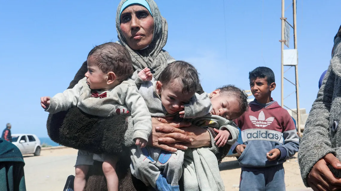Palestynka Nozha Awad z trojaczkami niedożywionymi z powodu braku żywności, wody i mleka w trakcie  ewakuacji z obleganego przez siły izraelskie szpitala Al Shifa. Strefa Gazy, 21 marca 2024 r. // Fot. Ramadan Abed / Reuters / Forum
