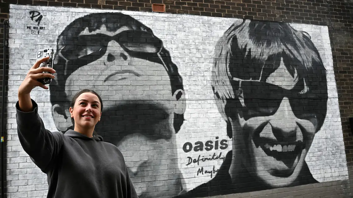 Mural przedstawiający członków zespołu Oasis: Liama ​​i Noela Gallagherów, wykonany przez artystę z Manchesteru Pic.One.Art. Na zdjęciu fanka zespołu Emily McShane. Burnage, przedmieścia Manchesteru, 27 sierpnia 2024 r. // Fot. Paul Ellis / East News