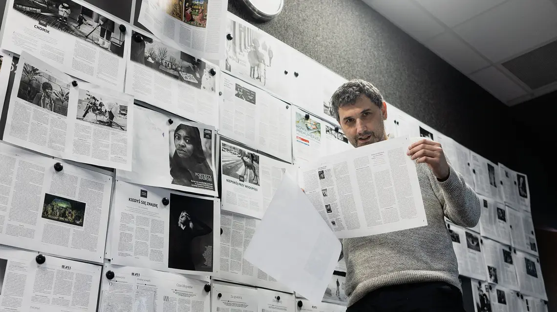 Przemysław Wilczyński przed tablicą z wydaniem światecznym TP51-52/2024. Redakcja Tygodnika Powszechnego przy ulicy Dworskiej w Krakowie. // Fot. Grażyna Makara
