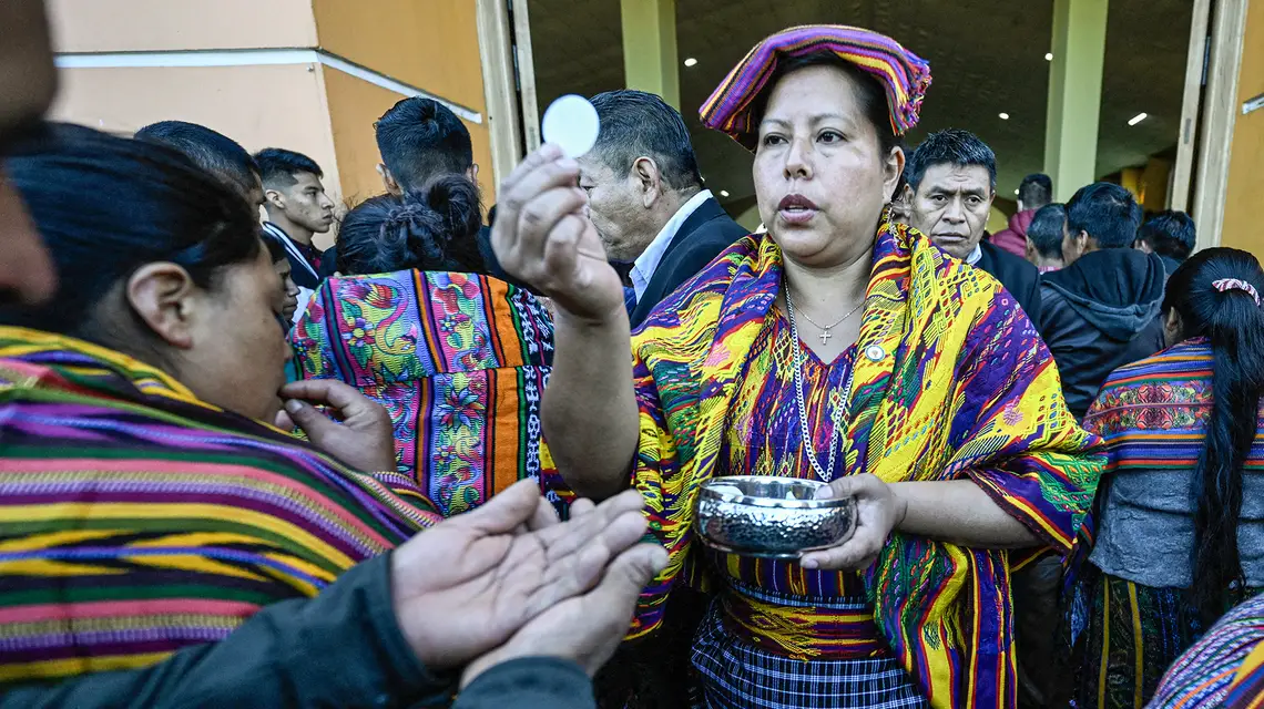 Kobieta ze społeczności rdzennej udziela komunii podczas mszy w gminie San Juan Sacatepequez. Gwatemala, 20 sierpnia 2023 r. // Fot. Luis Costa / AFP / East News