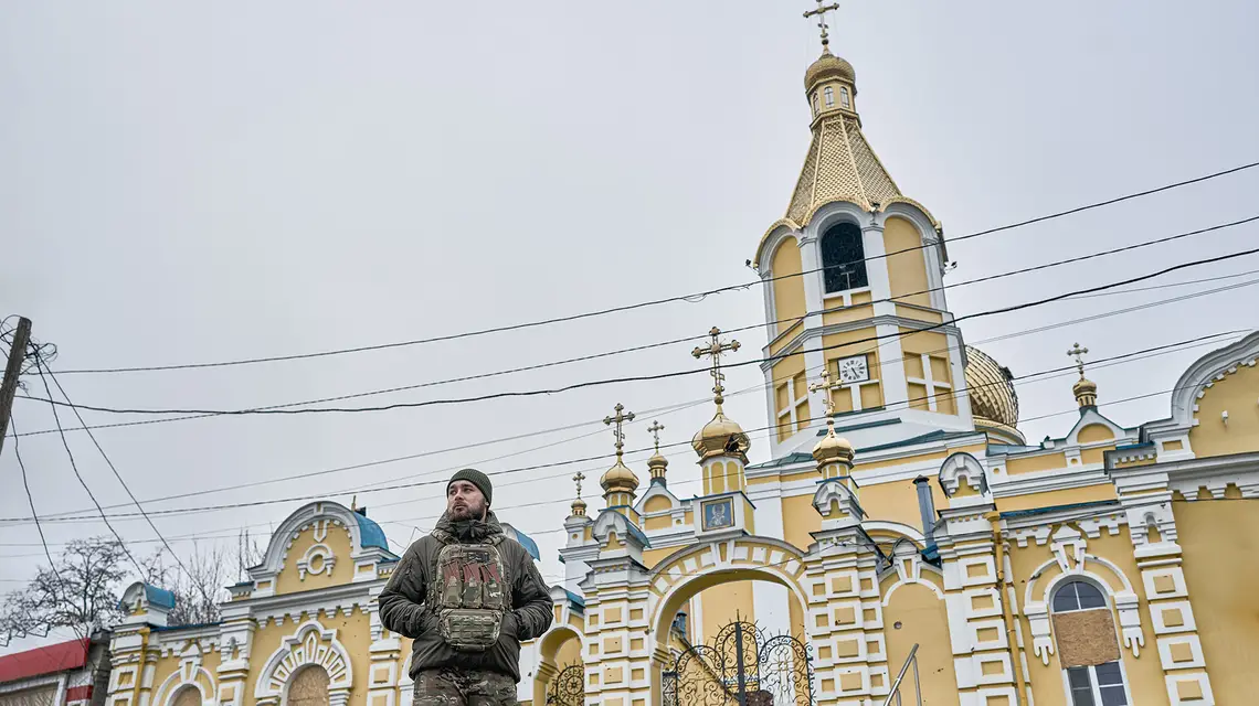 Ukraiński żołnierz przed cerkwią w Kupiańsku, przez który przebiega linia frontu. Ukraina, 25 grudnia 2024 r. // Fot. Kostiantyn Liberov / Libkos / Getty Images