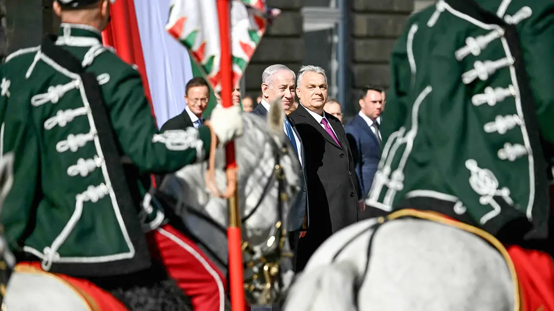Węgry to pierwszy kraj UE, który premier Izraela odwiedził od chwili, gdy jesienią 2024 r. Międzynarodowy Trybunał Karny wydał za nim list gończy. Premier Orbán nie zamierza go zatrzymać, choć Węgry przyjęły statut MTK. Na zdjęciu: Netanjahu i Orbán w Budapeszcie. Na pierwszym planie węgierska kompania honorowa. 3 kwietnia 2025 r. // Fot. Attila Kisbenedek / AFP / East News