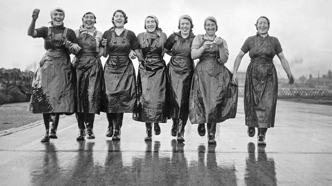 Przybyłe ze Szkocji „śledziowe dziewczyny” w drodze do pracy w porcie Great Yarmouth, około roku 1936. Praca była ciężka, ale dawała im szansę zarobienia własnych pieniędzy. W tamtych czasach były one w gronie najbardziej wyemancypowanych kobiet. // Fot. Trinity Mirror / Mirrorpix / Alamy / Be&W