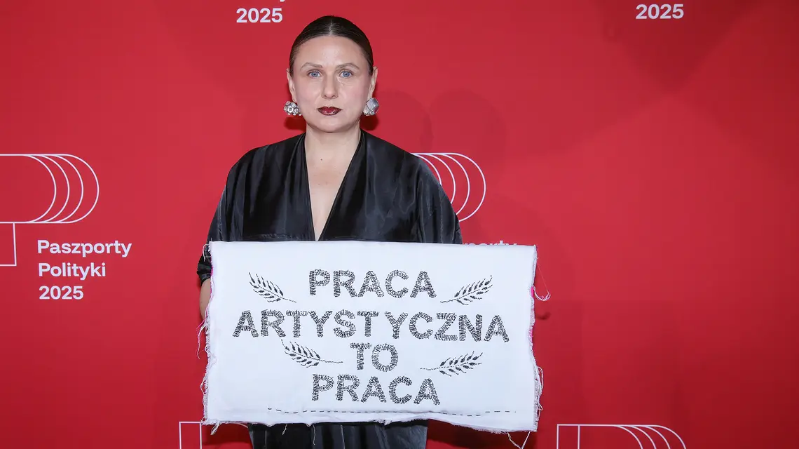 Monika Drożyńska z haftem „Praca artystyczna to praca", symbolizującym debatę o wynagrodzeniach dla artystów. Gala Paszportów Polityki 2025., 10 stycznia 2026 r. // Fot. Rafał Guz / PAP