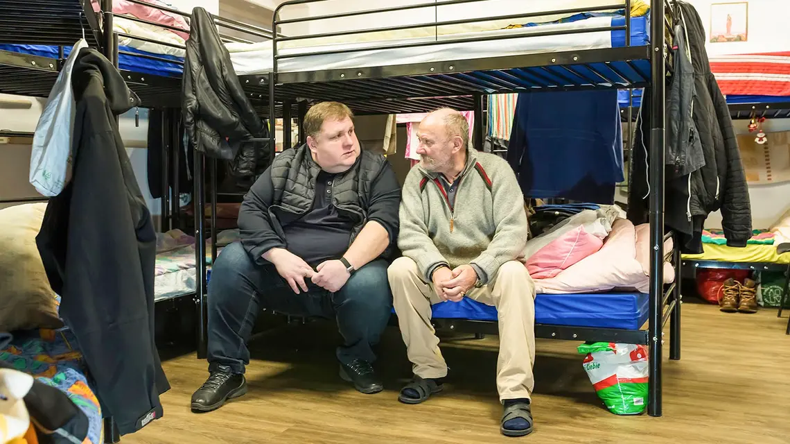 Ksiądz Sławomir Bar, proboszcz bazyliki w Bydgoszczy z jednym ze swoich podopiecznych w noclegowni znajdującej się w piwnicach kościoła. Bydgoszcz, styczeń 2025 r. // Fot. Piotr Ulanowski