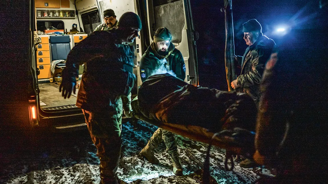 Medycy transportują rannego żołnierza. Po środku z czołówką to Ołeksandr. Obwód doniecki, luty 2023 r.  / PAWEŁ PIENIĄŻEK