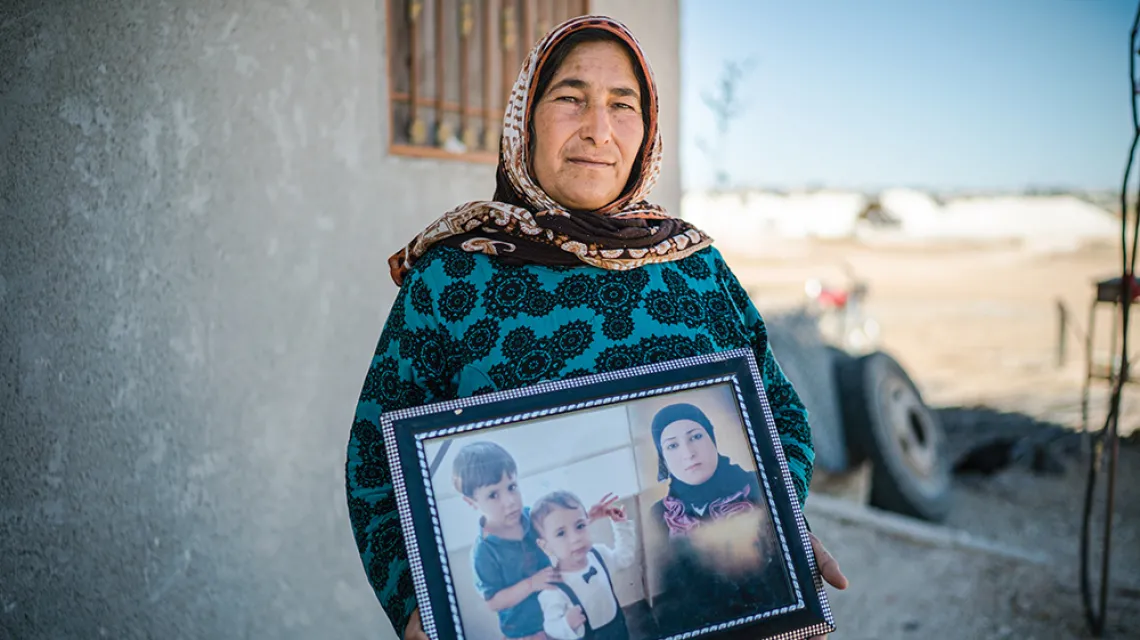 Fatma Senu trzyma w ręku kolaż, na którym są jej wnuki Alan i Galiba, a także córka Rihanna, Kobane, lipiec 2019 r. / PAWEŁ PIENIĄŻEK