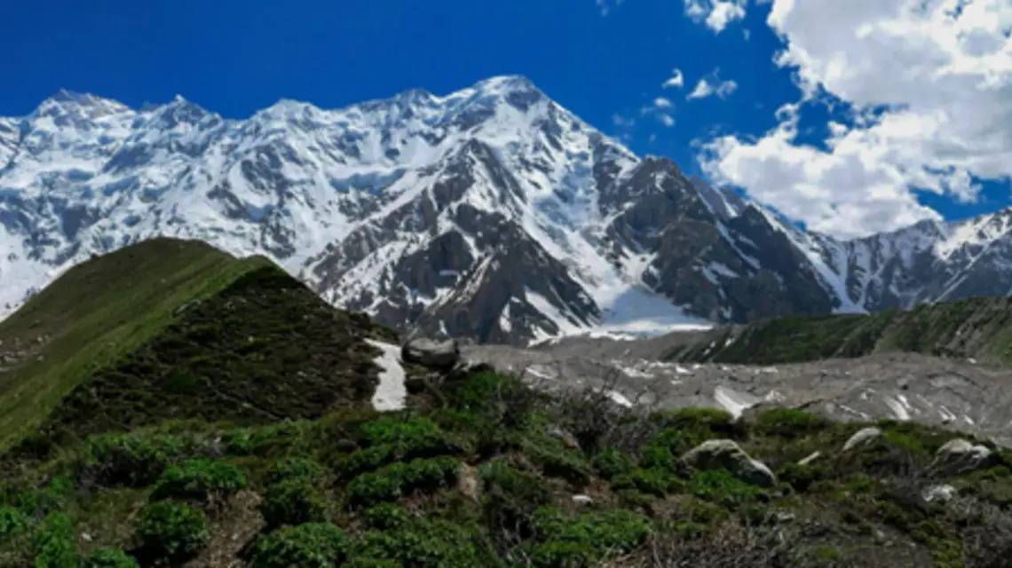 Masyw Nanga Parbat (8126 m) widziany z drogi z Baśniowej Polany do bazy pod północną ścianą – flanką Rakhiot. W środku zdjęcia wierzchołki wschodni (Silberzacken) i północny, pomiędzy nimi Srebrne Plateau, najwyższy z prawej Ganalo Peak (6606 m). / Fot. Waqas.usman / WIKI COMMONS
