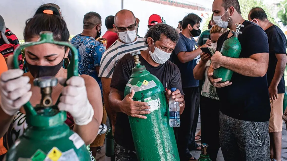 Bliscy chorych na COVID-19 czekają w kolejce na uzupełnienie butli z tlenem; ponieważ w szpitalach brakuje tlenu, krewni próbują załatwiać go na własną rękę. Manaus, 17 grudnia 2020 r. / ONNE RORIZ / BLOOMBERG / GETTY IMAGES