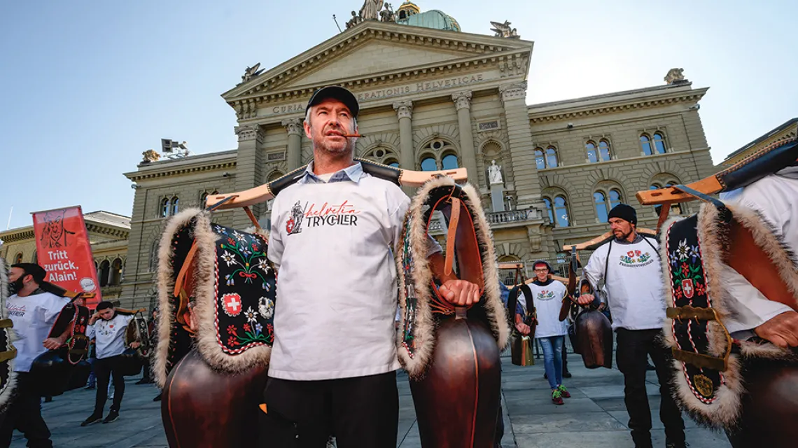 Protesty przeciw restrykcjom wspierają „wolnościowi trychlerzy”: grupa odwołująca się do ludowych tradycji i szwajcarskich mitów założycielskich, której symbolem jest krowi dzwon. Na zdjęciu: trychlerzy przed parlamentem w Bernie, 23 października 2021 r. / FABRICE COFFRINI / AFP