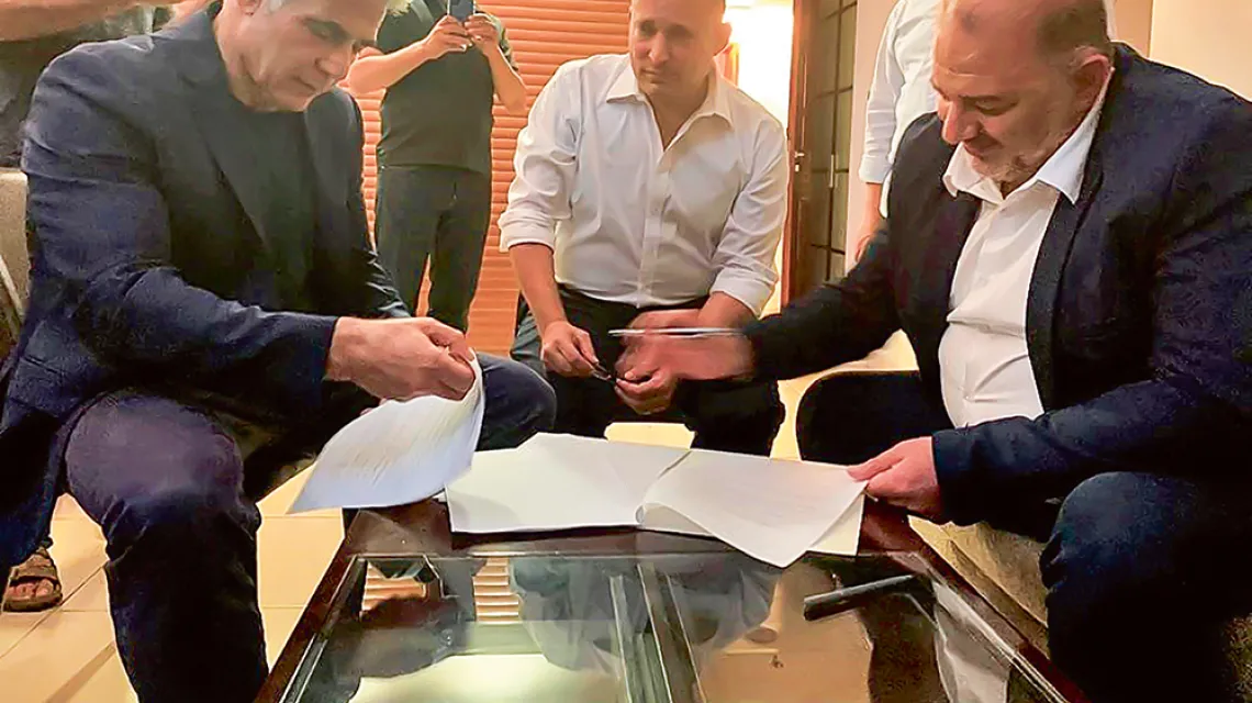 Od lewej: Jair Lapid, Naftali Bennett i Mansur Abbas podpisują porozumienieo koalicji rządowej. Ramat Gan, Izrael, 2 czerwca 2021 r. (zdjęcie zrobione smartfonem). / UNITED ARAB LIST RAAM / AFP / EAST NEWS