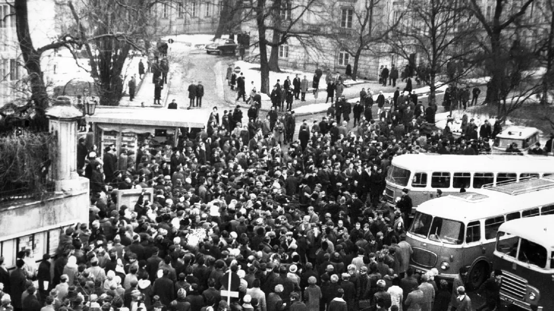Dziedziniec Uniwersytetu Warszawskiego, od bramy. Już są autobusy z tzw. aktywem, który zaczyna od rozmówz wiecującymi. Pod Auditorium Maximum (po lewej w głębi) stoi czarna wołga, takimi jeździł wyższy „aktyw”. Koło południa, piątek 8 marca 1968 r. / fot / 