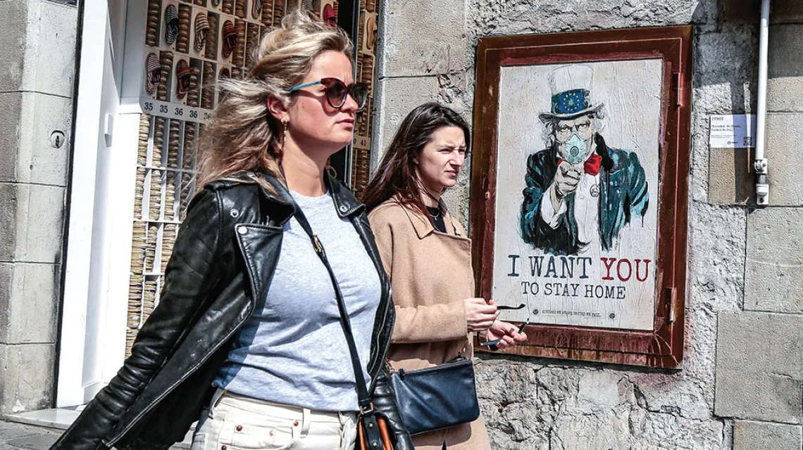 Turystki na ulicach, w tle graffiti „Chcę, abyś został w domu”, Barcelona, 13 marca 2020 r. / MIQUEL BENITEZ / GETTY IMAGES