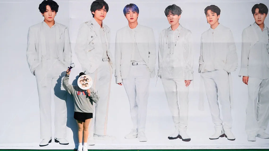 Fanka na tle bilbordu grupy BTS. Korea Południowa, Seul, październik 2019 r. / ED JONES / AFP / EAST NEWS
