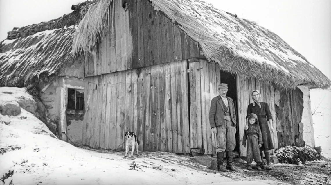 Rodzina chłopska z jednej z ponad 630 wsi, które zostały zniszczone podczas walk na przyczółkach nadwiślańskich. Zdjęcie wykonał wojskowy fotograf w roku 1949 (w opisie nie podano nazwy wioski), gdy zbudowano już przynajmniej prowizoryczne schronienia. / NARODOWE ARCHIWUM CYFROWE