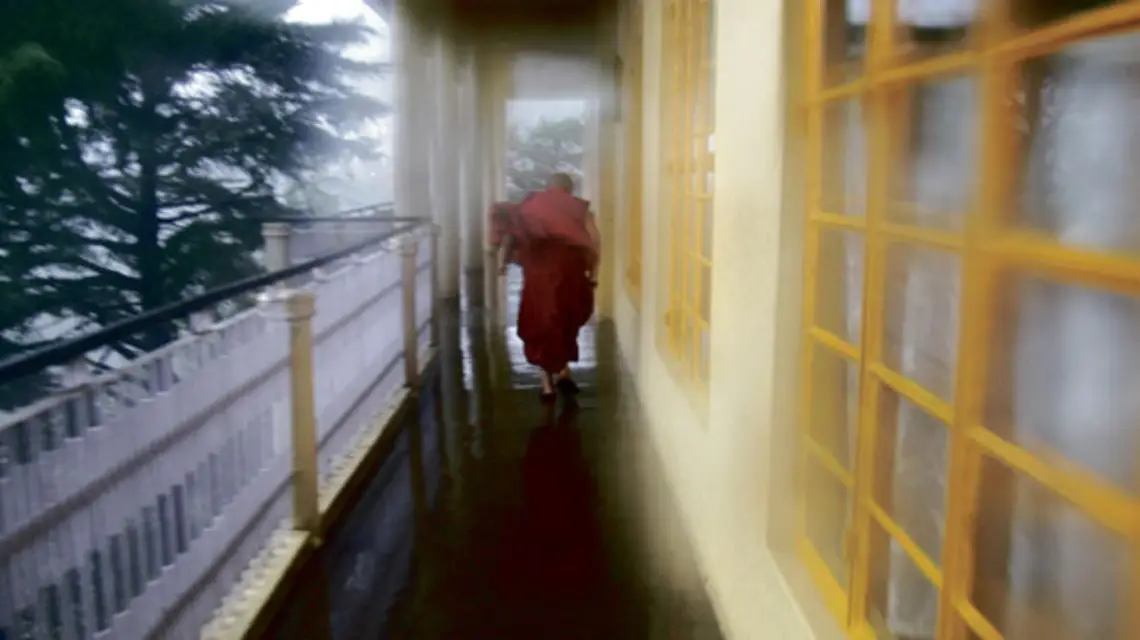 Stary mnich biegnie w podmuchach ulewy na tarasie świątyni Dalajlamy Tsuglagkhang, Dharamsala, maj 2008 /fot. Bartek Dobroch / 