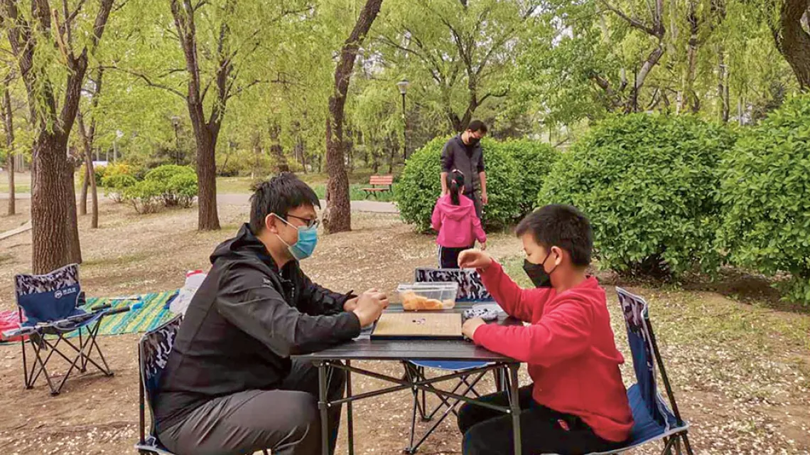 Ojciec gra z synem w wuziqi, tradycyjną chińską grę. Park Chaoyang w Pekinie, kwiecień 2020 r. / LÜ JIAN