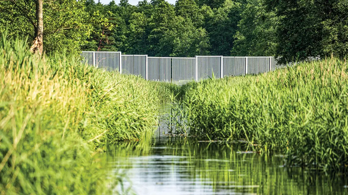 Narewka przepływa przez granicę 4 kilometry od centrum Białowieży. Docieram tam kajakiem, pilnując, by nie przekroczyć przepisowych 200 metrów od granicy. Wbrew rządowym zapowiedziom rzeka została przegrodzona płotem. Lipiec 2022 r. / KRZYSZTOF STORY