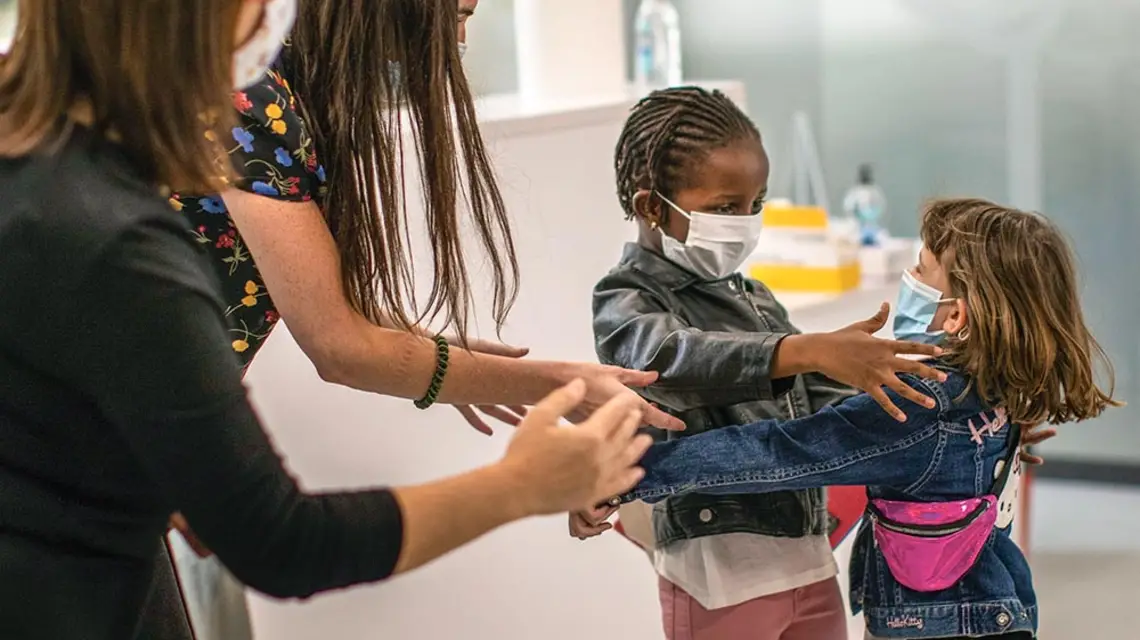 Nauczycielki z podstawówki w Barcelonie napominają sześciolatki Wendy i Oumou, aby nie przytulały się podczas powitania w pierwszy dzień po otwarciu szkoły. 8 czerwca 2020 r. / EMILIO MORENATTI / AP / EAST NEWS
