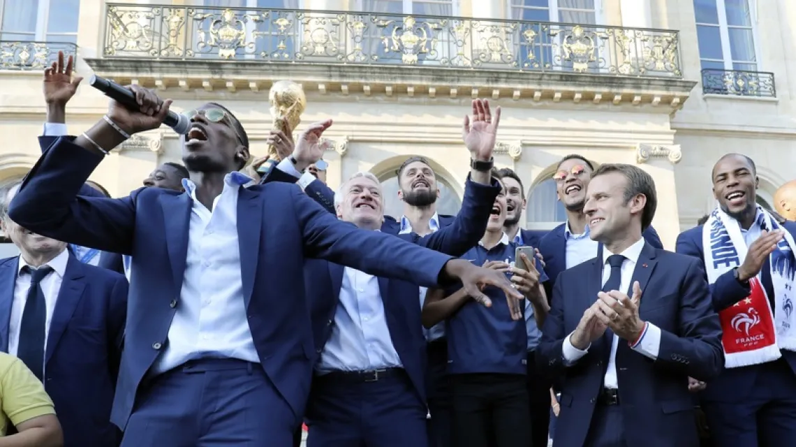 Paul Pogba (z mikrofonem) i pozostali reprezentanci Francji podczas przyjęcia przez Emmanuela Macrona (drugi z prawej) w Pałacu Prezydenckim, po powrocie drużyny ze zwycięskiego mundialu, 16 lipca 2018 / Fot. Ludovic Marin / AFP / East News / 