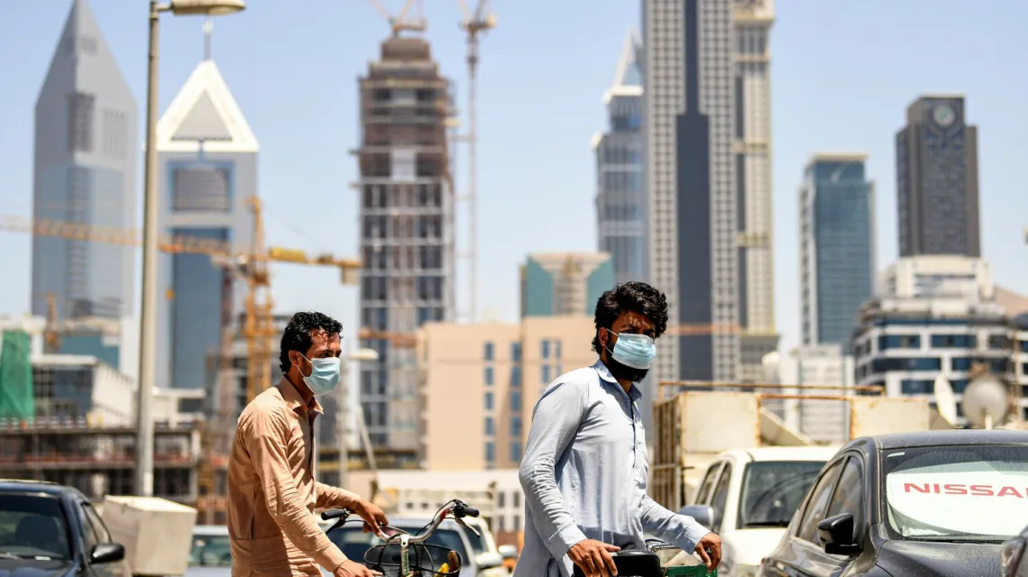 Imigranci pracujący w Dubaju pchają rowery przez dzielnicę Satwa / fot. KARIM SAHIB/AFP/East News / 