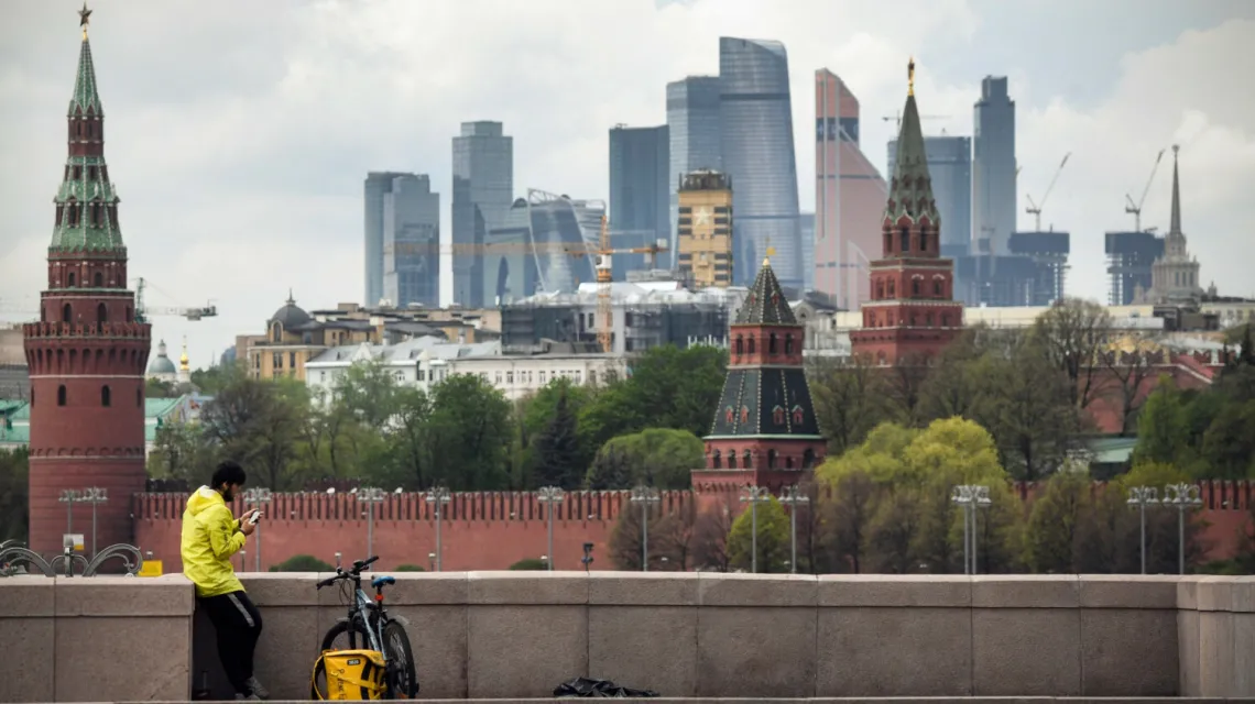 Kurier dostarczający jedzenie na moście w centrum Moskwy. W tle Kreml i budynki Moskiewskiego Międzynarodowego Centrum Biznesu, 6 maja 2020 r. / FOT. ALEXANDER NEMENOV/AFP/East News / 
