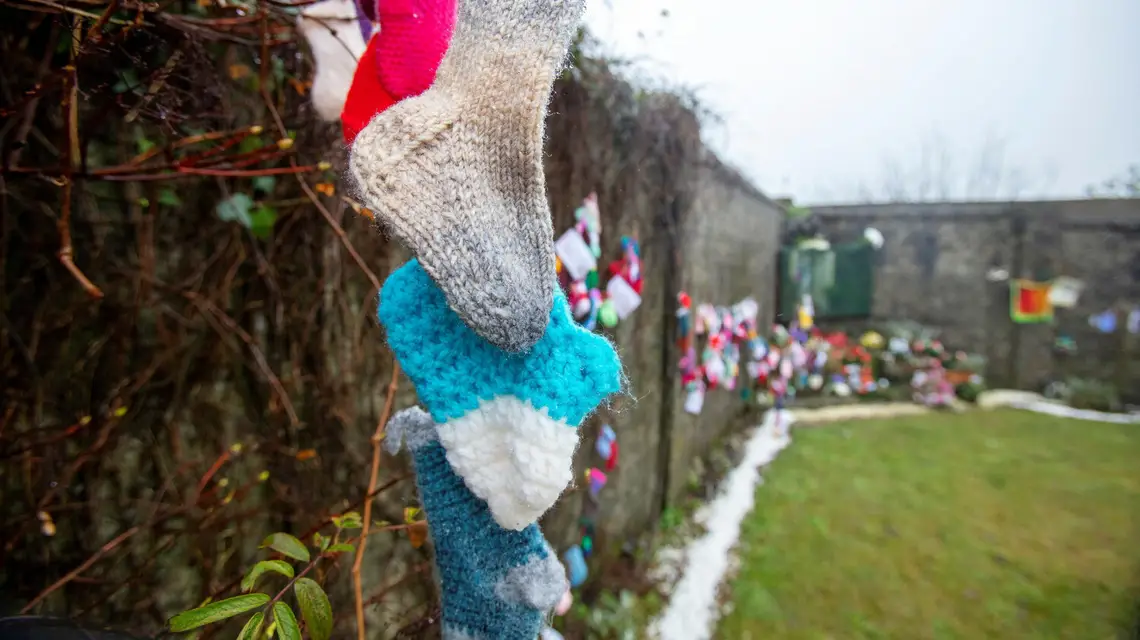 Dziecięce skarpetki na murze dawnego "domu opieki" w Tuam, gdzie zakonnice pochowały ok. 800 niemowląt. Urodzone z ciąży pozamałżeńskiej, zostały uznane przez siostry za grzeszne i pochowane bezimiennie. / Fot. Paul Faith / AFP / East News / 