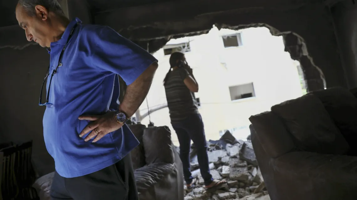 Izraelska rodzina ogląda zrujnowane mieszkanie po uderzeniu palestyńskiej rakiety, Petah Tikva (środkowy Izrael), 13 maja 2021 r. / Fot. Oded Balilty / AP Photo / East News / 