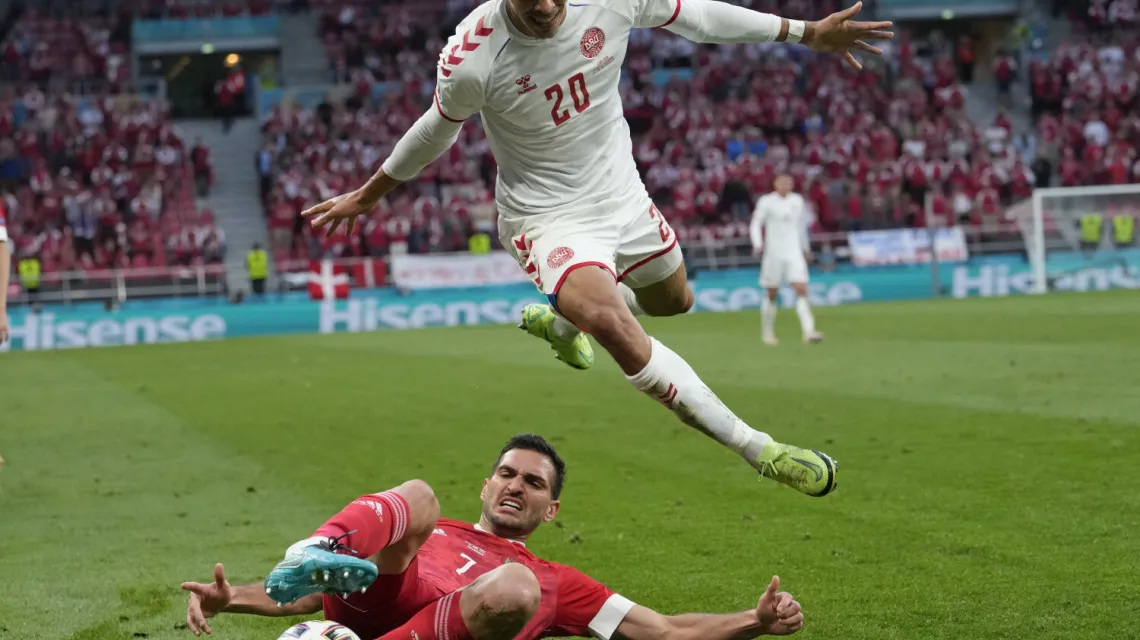 Duńczyk Jusuf Poulsen przeskakuje nad Rosjaninem Magomiedem Ozdojewem w meczu Dania-Rosja, Kopenhaga, 21 czerwca 2021 r. / Fot. Martin Meissner / AP Photo / East News / 