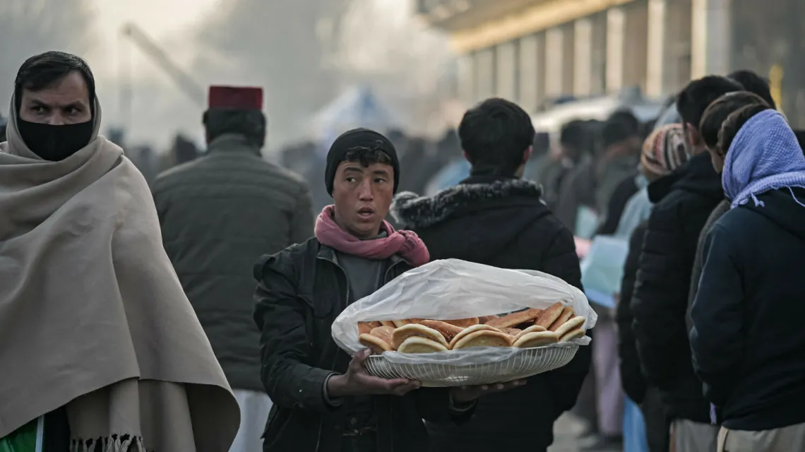 Mężczyzna sprzedaje chleb w kolejce do biura paszportowego w Kabulu, 19 grudnia 2021 / fot. MOHD RASFAN/AFP/East News / 