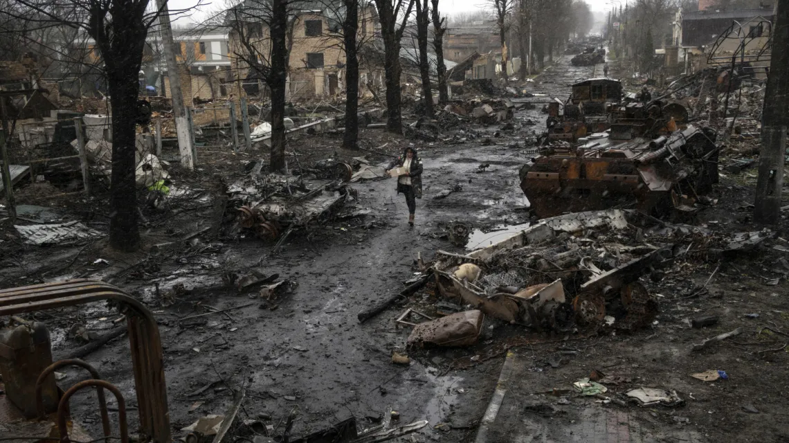 Kobieta idzie wśród zniszczonych rosyjskich czołgów. Bucza, 3 kwietnia / fot. AP/Associated Press/East News / 