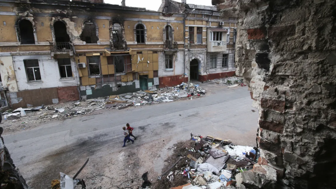 Dzieci idą wśród zniszczonych budynków w Mariupolu. Miastu grozi epidemia chorób takich jak cholera czy czerwonka. 25 maja 2022 r. / fot. AP/Associated Press/East News / 