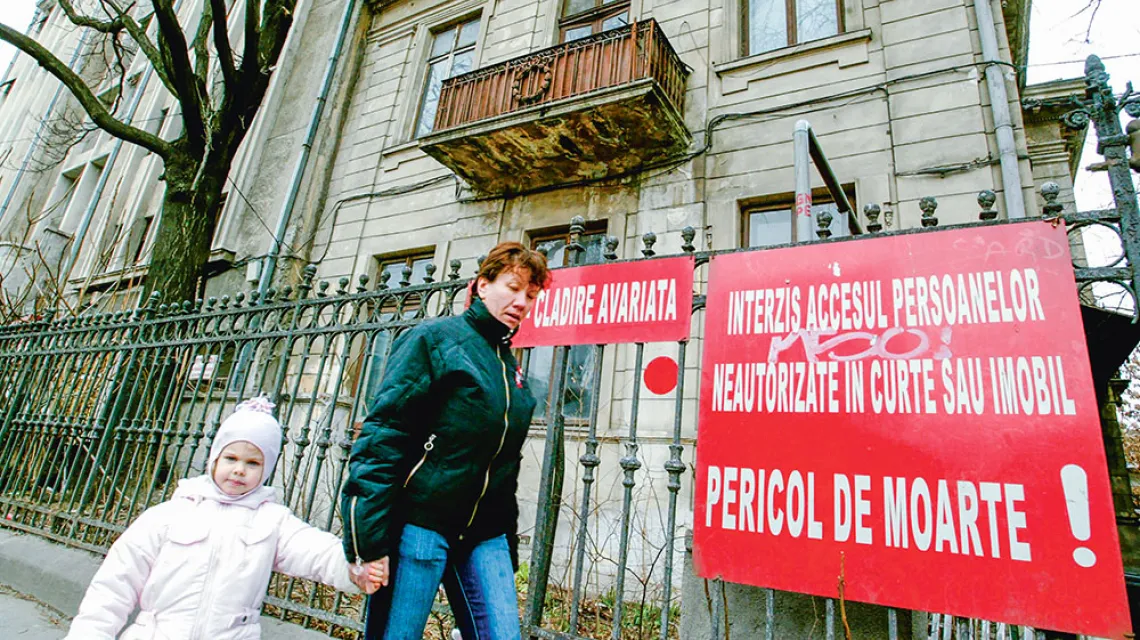 Przechodnie przed kamienicą oznaczoną czerwoną kropką i napisem „Uszkodzony budynek”, „Niebezpieczeństwo śmierci”. Na dwa dni przed 40. rocznicą trzęsienia z 1977 r. i na dzień przed fałszywym alarmem, który poderwał kilkaset tysięcy mieszkańców rumuńskie / DANIEL MIHAILESCU / AFP