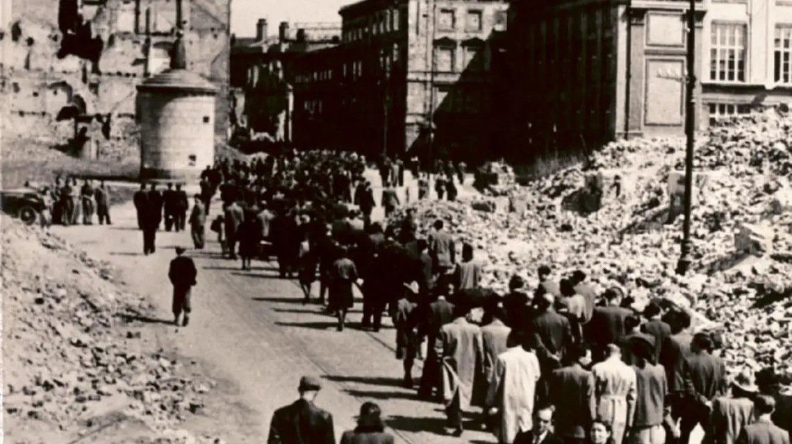 IV rocznica powstania w getcie. Pochód idzie obok odbudowanej Biblioteki Judaistycznej, siedziby CKŻP (Centralny Komitet Żydów Polskich, później ŻIH). Po prawej stronie ruiny Wielkiej Synagogi / Fot. Odbitka w zbiorach ŻIH