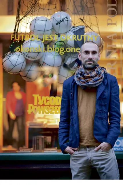 Michał Okoński stoi na tle witryny (zaprojektowanej przez Monikę Drożyńską) Księgarni pod Globusem / Fot. Grażyna Makara