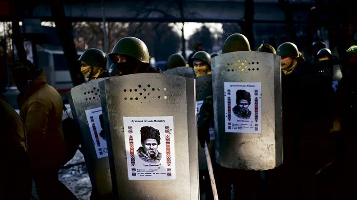 Ukraińscy powstańcy z Samoobrony Majdanu ze zdobycznymi tarczami milicyjnymi, na których umieścili wizerunek Tarasa Szewczenki. Kijów, luty 2014 r. / Fot. Martin Bureau / AFP / EAST NEWS
