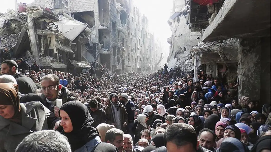 Mieszkańcy Jarmuk, obleganego od miesięcy przez wojska Asada, wylegli z kryjówek, by zdobyć trochę żywności rozdzielanej przez organizacje międzynarodowe; styczeń 2014 r. / Fot. UNRWA / REUTERS