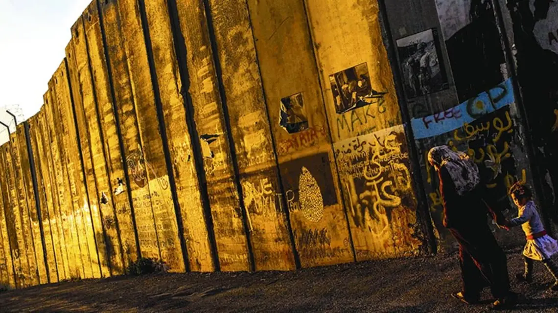 Palestyńska rodzina przy izraelskim „murze bezpieczeństwa”, przez Palestyńczyków zwanym „murem aneksyjnym”; Betlejem, 2010 r. / Fot. Bernat Armangue / AP / EAST NEWS