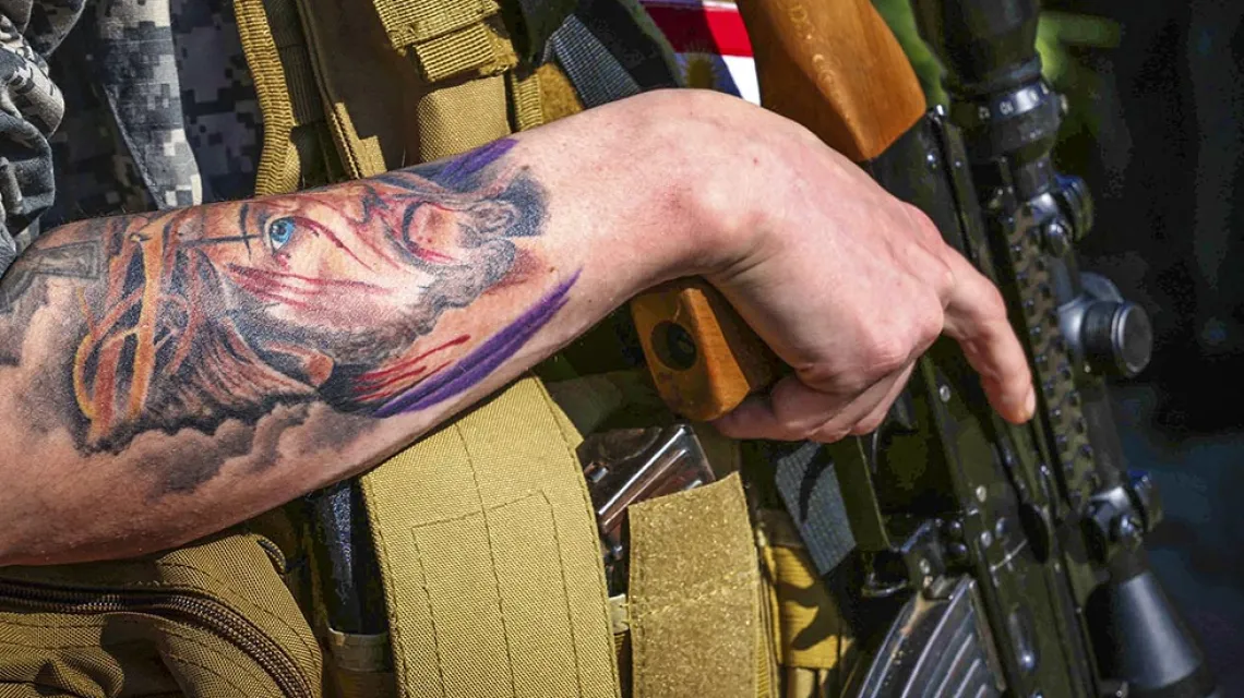 Chrystus w koronie cierniowej na tatuażu jednego z zachodnich ochotników walczących w szeregach chrześcijańskiej samoobrony Dwekh Nawsha; wioska Al-Qosh w północnym Iraku, 2015 r. / Fot. Safin Hamed / AFP / EAST NEWS