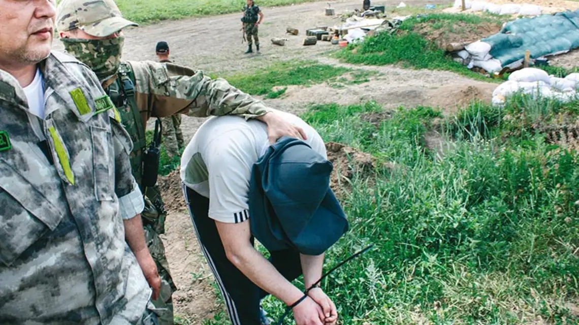 Ukraiński negocjator Wasyl Budik (pierwszy z lewej) i jeniec Siergiej Małyszkowski prowadzony na wymianę. / Fot. Paweł Reszka